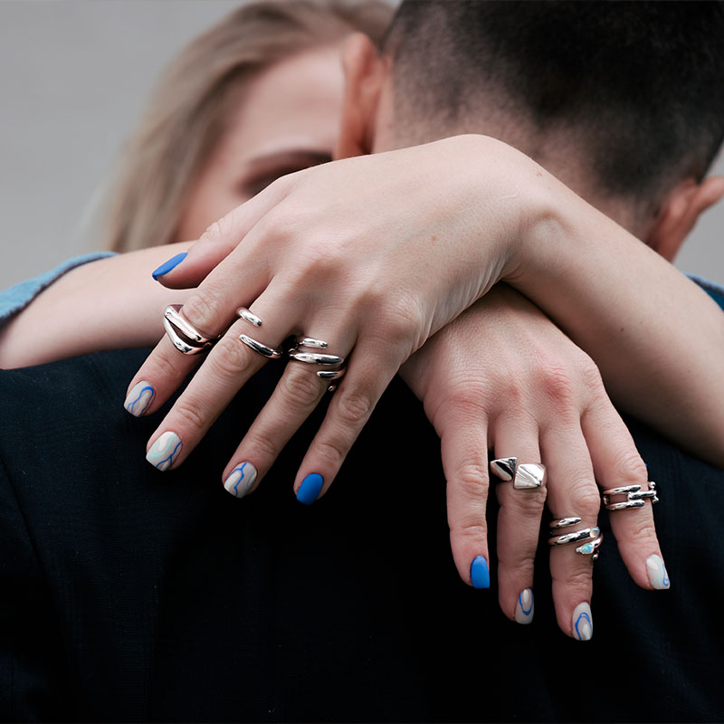 An image of woman's hands hugging a man while wearing multiple Etherea Gallery rings