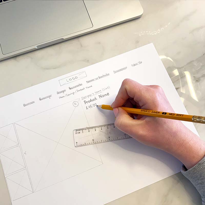 A photo of me drawing a paper wireframe for a product page